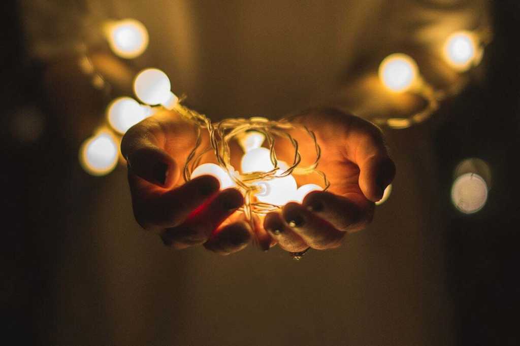 hands hold a string of lightbulbs hands at sunset / ideas / brainstorming / invention / innovation