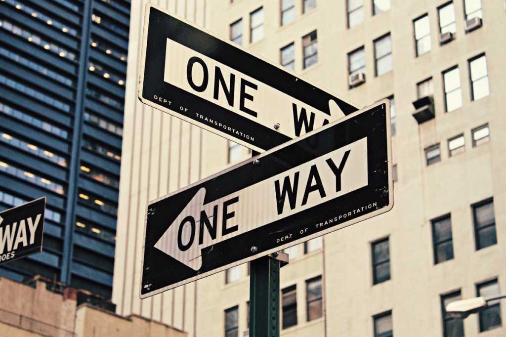 one way sign direction two way city streets buildings choice direction by brenden church unsplash