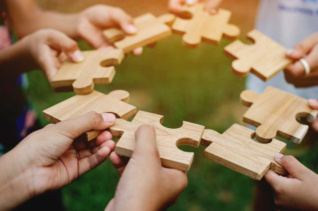 Circle of hands holding puzzle pieces