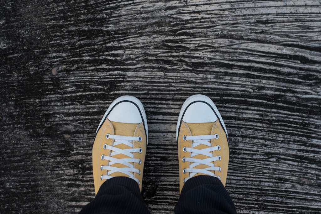 Top view of black pants yellow sneakers hipster standing on concrete floor