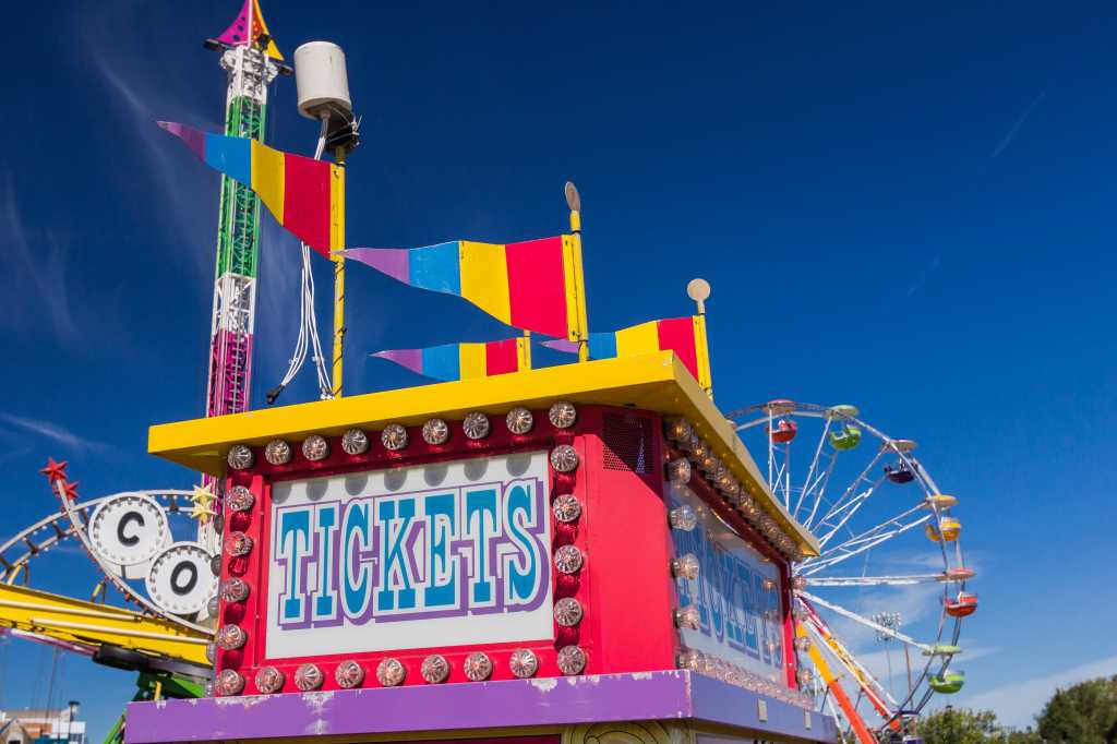 shutterstock 490364485 tickets sign on carnival ticket booth with ferris wheel in background