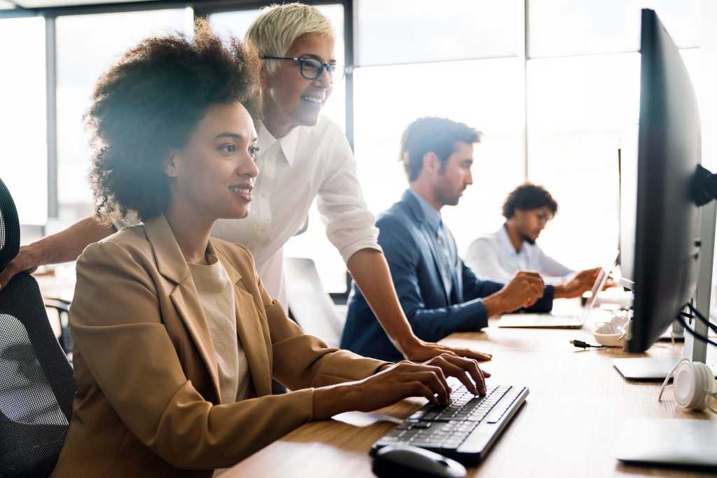 A team of people working together in an office workspace at computers.